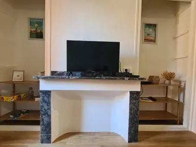 a fireplace with a tv on top of it at Douces Vagues - hypercentre climatisé in Narbonne