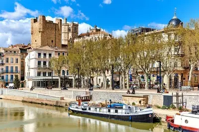 a boat in a river in front of a city at Douces Vagues - hypercentre climatisé in Narbonne