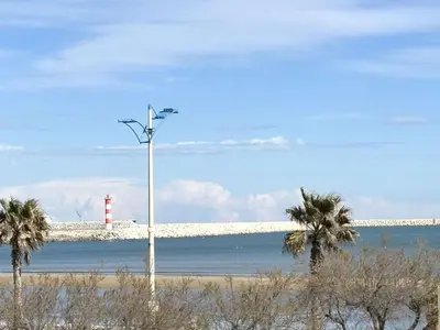 a light pole on the beach with a lighthouse at Appart 2 pièces Cabine PORT LA NOUVELLE PN590-022 in Port-la-Nouvelle