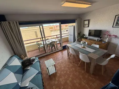a living room with a table and a view of a kitchen at Appart 2 pièces Cabine PORT LA NOUVELLE PN590-022 in Port-la-Nouvelle