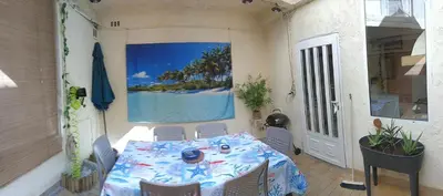 a table and chairs on a patio with a picture of the ocean at La Voile Méditerranéenne in Port-la-Nouvelle