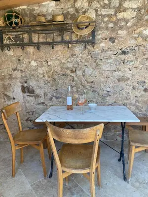 a table with two chairs and a bottle of wine at Chambre d'Hôtes Dahlia - Boutenac in Boutenac