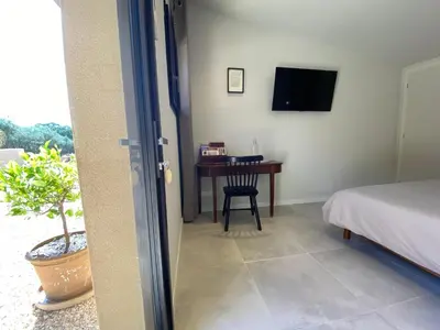 a bedroom with a bed and a desk with a television at Chambre d'Hôtes Dahlia - Boutenac in Boutenac