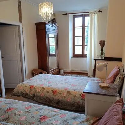 a bedroom with two beds and a chandelier at Les lits de Montbel B&B in Sonnac-sur-lʼHers