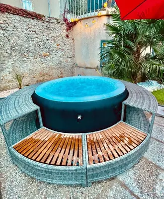 a hot tub sitting on a bench with an umbrella at Babouz Cottage in Mirepoix