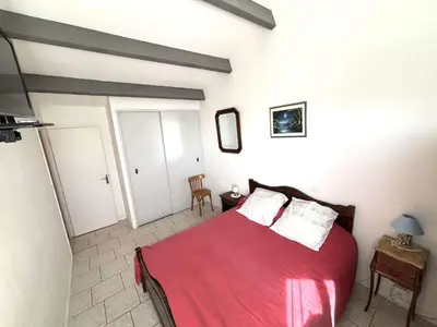 a bedroom with a bed with red sheets and white pillows at Maison 8 couchages - Port la Nouvelle - PN000-048 in Port-la-Nouvelle