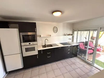 a kitchen with black cabinets and a white refrigerator at Maison 8 couchages - Port la Nouvelle - PN000-048 in Port-la-Nouvelle