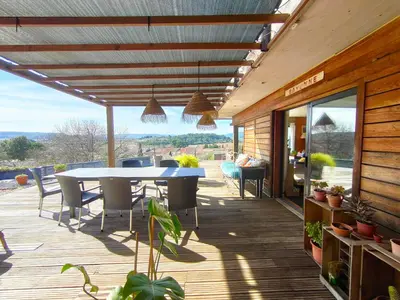 a patio with a table and chairs on a deck at Maison contemporaine en bois au coeur des Corbières in Ferrals-lès-Corbières