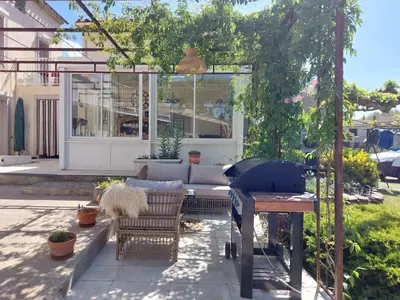 a patio with a grill and chairs in a yard at La cazabanelle in Villegly