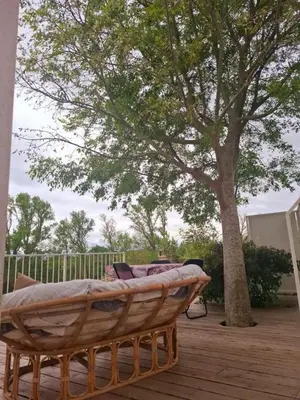 a wooden bed sitting on a deck next to a tree at La cazabanelle in Villegly