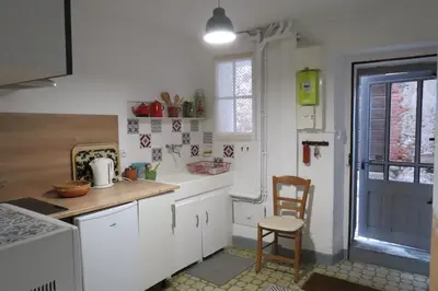 a kitchen with white cabinets and a table and a chair at BELESTAGITE7 Pays Catalan 66 in Bélesta