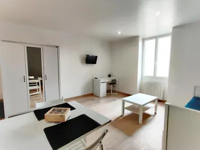 a white living room with a table and a tv at Le Nid du Pont Neuf in Pamiers