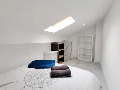 a white bedroom with a bed with a blue blanket at L'Atelier des Carmes in Pamiers