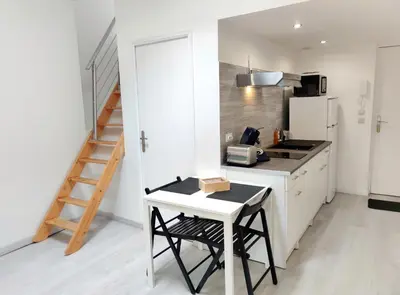a kitchen with a counter and a table and a refrigerator at L'Atelier des Carmes in Pamiers