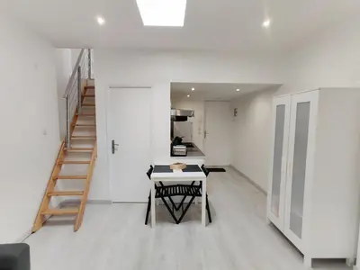 a white kitchen with a table and a staircase at L'Atelier des Carmes in Pamiers