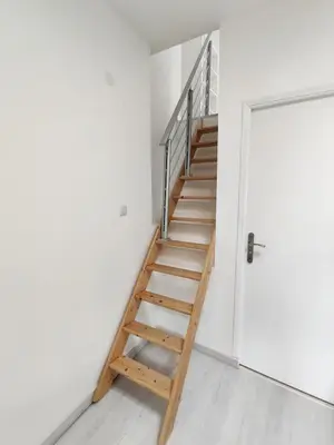 a wooden staircase in a white room with a door at L'Atelier des Carmes in Pamiers