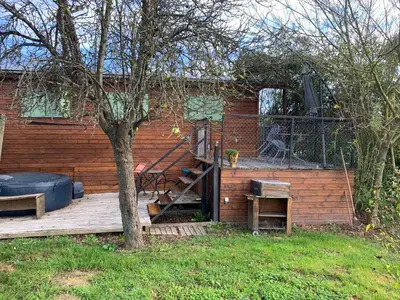a house with a wooden deck with a tree at La roulotte de Plajoulet in Mirepoix