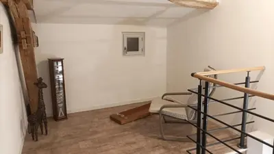 a living room with a staircase and a chair at Gite centre village Burlats in Burlats
