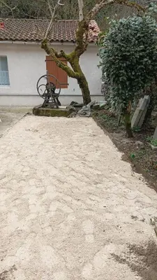 a dirt driveway with a tree in front of a house at Gite centre village Burlats in Burlats