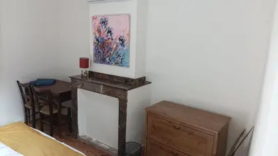 a room with a fireplace with a table and a painting at Gite centre village Burlats in Burlats
