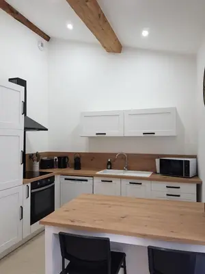 a kitchen with white cabinets and a wooden counter top at Maison Stellas in Fontiès-dʼAude