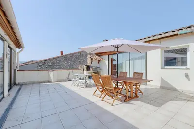 a patio with a wooden table and an umbrella at Gîtes Tautavel in Tautavel