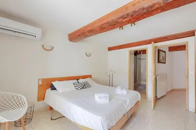 a white bedroom with a bed and a chair at Gîtes Tautavel in Tautavel