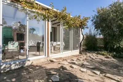a conservatory with glass doors and a patio at Maison avec jardin clos dans residence in Gruissan