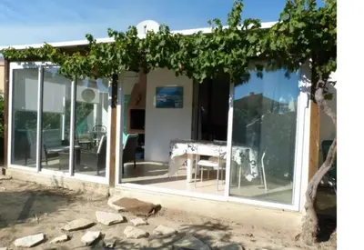 a conservatory with glass doors and a table at Maison avec jardin clos dans residence in Gruissan