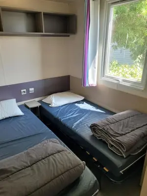 two beds in a room with a window at mobile home climatisé, 3 chambres in Port-la-Nouvelle