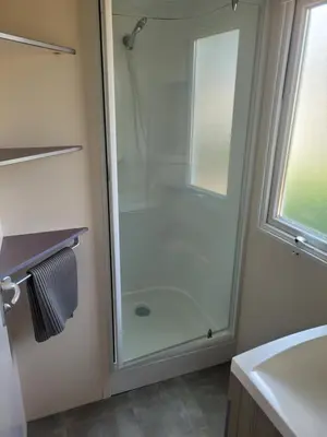 a glass shower in a bathroom with a sink at mobile home climatisé, 3 chambres in Port-la-Nouvelle
