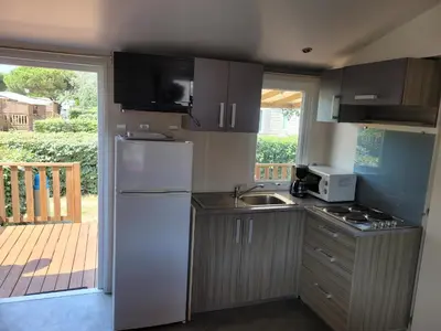 a kitchen with a white refrigerator and a sink at mobile home climatisé, 3 chambres in Port-la-Nouvelle