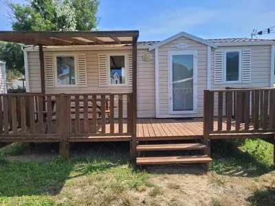 a large wooden deck with a porch and a house at mobile home climatisé, 3 chambres in Port-la-Nouvelle