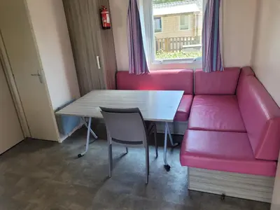 a living room with a pink couch and a table at mobile home climatisé, 3 chambres in Port-la-Nouvelle