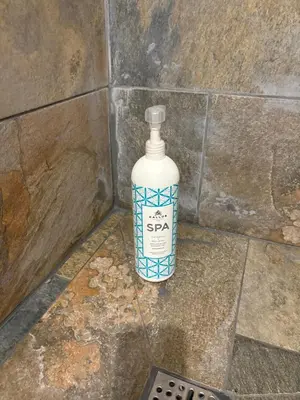 a bottle of soap sitting on the floor in a bathroom at Ma petite chaumière in Bouilhonnac