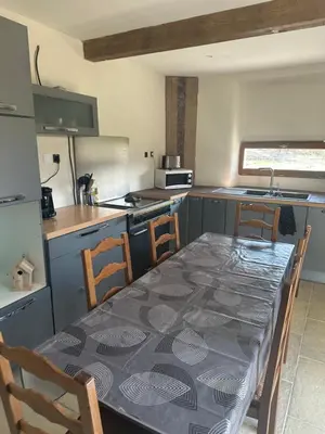 a kitchen with a table and some chairs and a kitchen with a table at Ma petite chaumière in Bouilhonnac