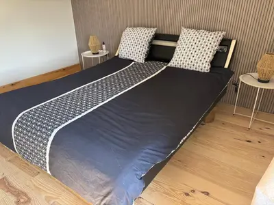 a large bed in a room with two tables at Ma petite chaumière in Bouilhonnac