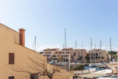 a marina with boats in the water and buildings at Le Rivage du Nilautom in Gruissan