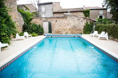 a swimming pool with chairs and a building at CHAMBRE D'HOTE Ô MAZETTE visite de l'Aude in Fabrezan