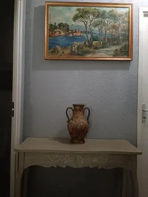 a vase sitting on a table under a painting at Chambre d'hôtes petit déjeuner compris in Carcassonne