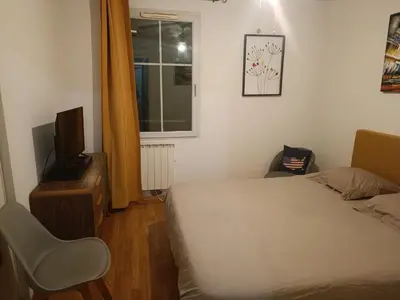 a bedroom with a bed and a tv and a chair at Chambre d'hôtes petit déjeuner compris in Carcassonne
