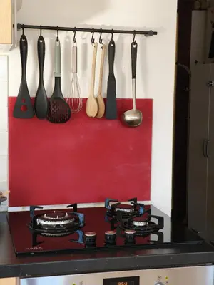 a stove top with utensils hanging on a wall at Terrasse, vue & Parking - Carnaval à pied in Limoux