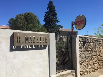 a sign on a wall with a gate and a building at O'MAZETTE CHAMBRE D'HOTE ROMANTIQUE visite de l'aude in Fabrezan