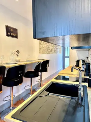 a kitchen with a sink and some black bar stools at The62 in Carcassonne