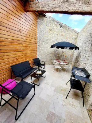 a patio with chairs and an umbrella and a table at Maison au calme - Clim - Wi-Fi - terrasse et cours in Salles-d'Aude