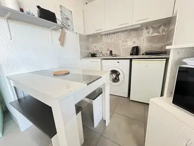 a kitchen with a white table and a washing machine at Lo Nidou Gruissan in Gruissan