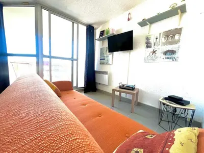 a living room with a couch and a large window at Lo Nidou Gruissan in Gruissan
