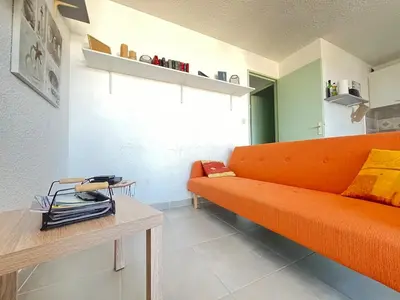 a living room with an orange couch and a table at Lo Nidou Gruissan in Gruissan