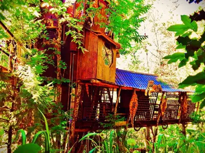 a tree house with a cat sitting on a balcony at Le Vertige du Tigre in Courniou