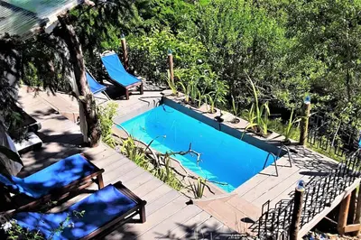 a swimming pool with two blue chairs on a deck at Le Vertige du Tigre in Courniou
